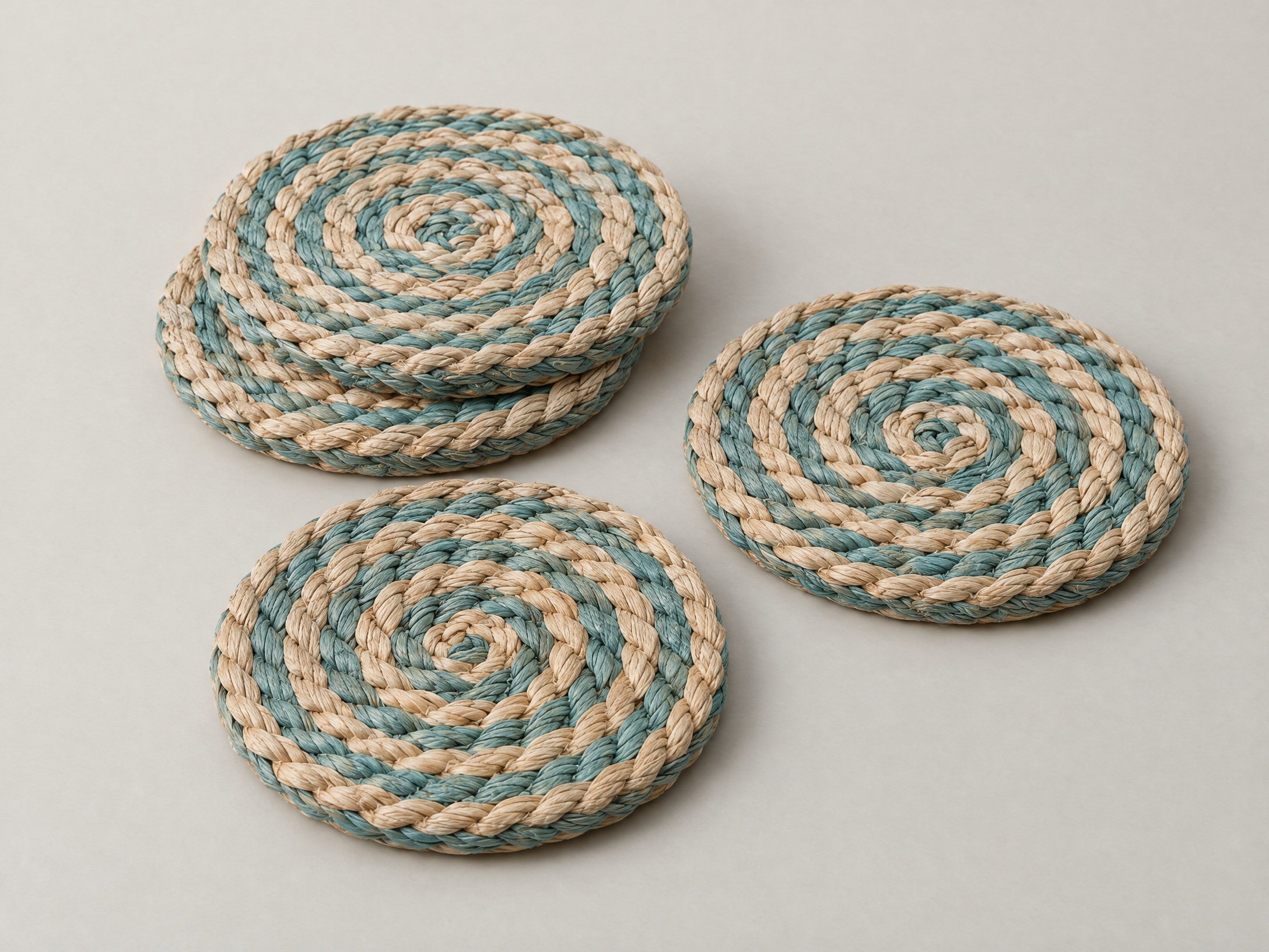 Original AI-generated concept of four round woven coasters in sand and muted teal
